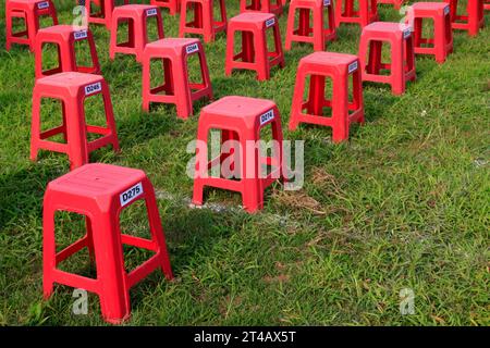 Sgabelli in plastica nei cespugli di un parco Foto Stock