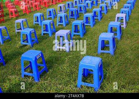 Sgabelli in plastica nei cespugli di un parco Foto Stock