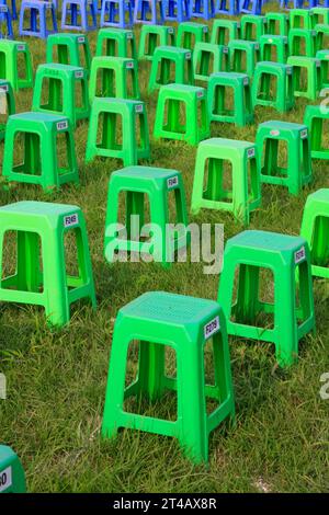 Sgabelli in plastica nei cespugli di un parco Foto Stock