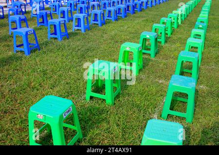 Sgabelli in plastica nei cespugli di un parco Foto Stock