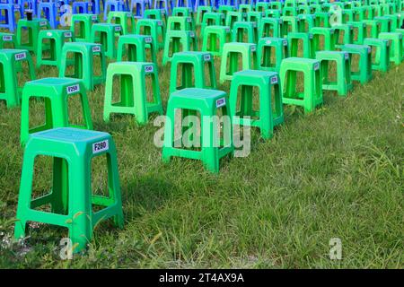 Sgabelli in plastica nei cespugli di un parco Foto Stock