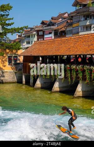 Surfista sul fiume Aare nella città di Thun dal ponte Untere Schleuse in una soleggiata giornata estiva, Oberland Bernese, Cantone di Berna, Svizzera Foto Stock