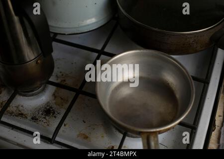 Vecchia cucina. Piatti sul piano cottura a gas. Secchio dell'acqua in alluminio. Cucina con cose vecchie. Foto Stock