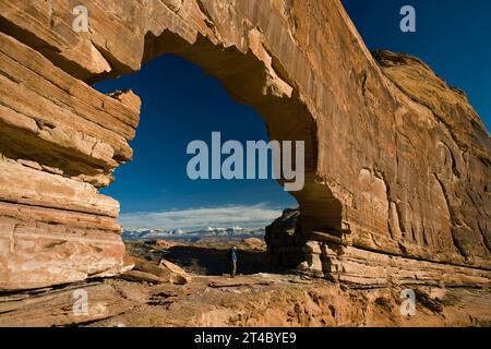 Uomo in piedi sotto l'arco nel deserto, Moab, Utah. Foto Stock