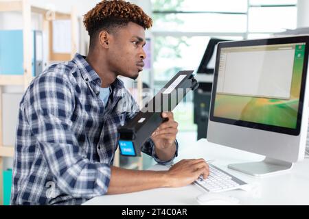 tecnico che sta effettuando ricerche su una cartuccia di toner sul computer Foto Stock