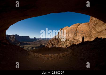 Persona in piedi nell'alcova vicino alle rovine indiane con vista del deserto, Canyonlands National Park, Utah. Foto Stock