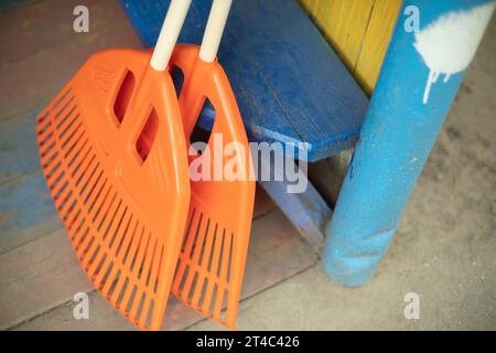 Scopa arancione. Strumento di pulizia. Strumento giardino. Setole in plastica per la raccolta di scarichi a secco. Foto Stock