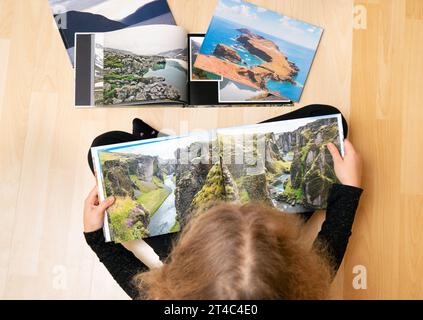 Bambino che guarda i veri libri fotografici di viaggio cartacei stampati sul piano casa. Il fotografo ha il copyright delle foto nei libri, sono fatte a mano. Foto Stock