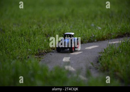 Trattore giocattolo su una strada in erba alta Foto Stock