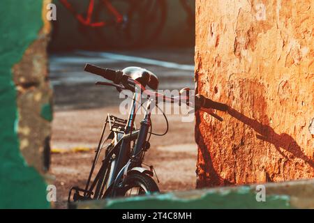 Bicicletta vecchia appoggiata alla parete usurata, messa a fuoco selettiva Foto Stock