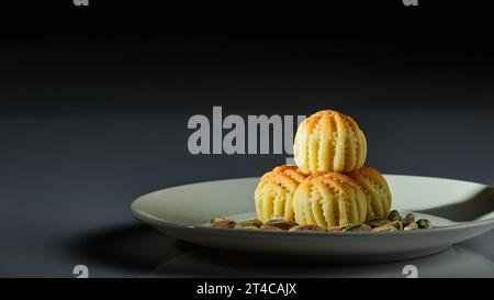 Un piatto di dolci arabi con pistacchi raffigurati su uno sfondo bianco e uno sfondo grigio e nero Foto Stock