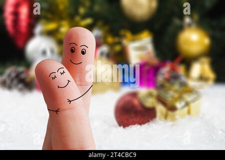 Volti di dita che si abbracciano l'un l'altro isolati su sfondo decorato a Natale. Famiglia felice che festeggia il giorno di Natale Foto Stock