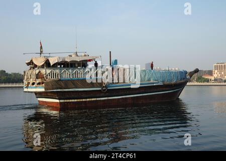 29 ottobre 2023, Dubai, Emirati Arabi Uniti. Una mattina presto da Dubai Abra con edificio tradizionale e barche. È una modalità di viaggio comune per l'uomo e per i turisti. Foto Stock