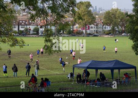 Con la città in lontananza, i calciatori dilettanti giocano una partita in un campionato di lingua spagnola al Ruskin Park, uno spazio verde pubblico a Lambeth sud di Londra, il 28 ottobre 2023, a Londra, in Inghilterra. Foto Stock