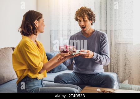 Ritratto della giovane coppia felice. La donna sta facendo un regalo al suo uomo. Foto Stock