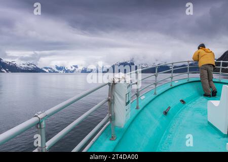 Turista in gita in barca nel nord-ovest dei fiordi di Kenai sulla strada per il ghiacciaio nordoccidentale nel Kenai Fjords National Park in Alaska. Foto Stock