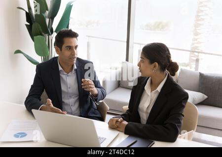 Due colleghi d'affari indiani in abiti formali che parlano sul posto di lavoro Foto Stock