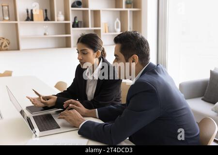 Due colleghi professionisti indiani concentrati che discutono di applicazioni online Foto Stock