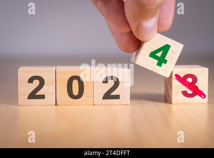 Mano che cambia il numero da 3 a 4 per simboleggiare il cambiamento dell'anno dal 2023 al 2024. Foto Stock