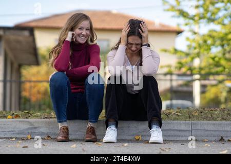 Felice falso amico che consola una donna disperata per strada. Finto concetto di amico Foto Stock