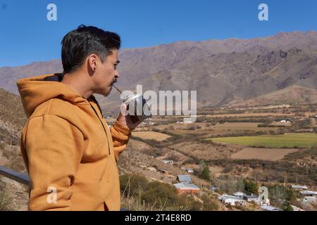 Primo piano di un uomo latino marrone in solitudine e rilassato compagno di bevute che si gode il paesaggio da un balcone a tafi del Valle, Tucuman, Argentina. arge Foto Stock