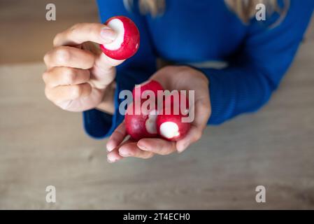 La donna tiene il cibo in mano. La ragazza tiene un ravanello. Si irradia nelle mani delle donne. Red Radish Foto Stock