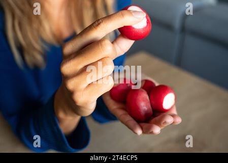 La donna tiene il cibo in mano. La ragazza tiene un ravanello. Si irradia nelle mani delle donne. Red Radish Foto Stock