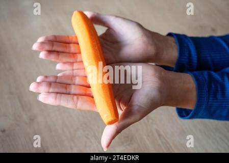 La donna tiene il cibo in mano. la ragazza tiene le carote in mano. Carote arancioni in mano. Foto Stock