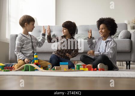 I piccoli ragazzi giocano insieme con la ferrovia in legno in un accogliente soggiorno Foto Stock