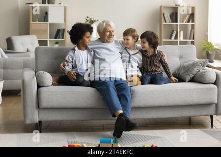 Il bisnonno in pensione parla con tre bisnipoti multietnici Foto Stock