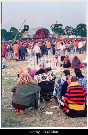 GLASTONBURY FESTIVAL, 1995: Un fan della sedia a rotelle al secondo NME Stage Field e folla nell'ultima domenica sera al Glastonbury Festival, Pilton Farm, Somerset, Inghilterra, 25 giugno 1995. Nel 1995 il festival ha celebrato il suo 25° anniversario. Non c'era nessuna fase piramidale quell'anno, dato che era bruciata. Foto: ROB WATKINS Foto Stock