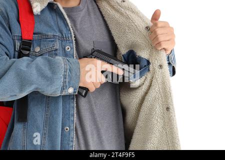 Studente maschio con pistola in tasca su sfondo bianco, primo piano. Concetto di sparatoria scolastica Foto Stock