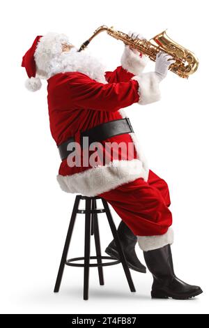 Foto del profilo completo di Babbo Natale seduto su una sedia e che suona un sassofono isolato su sfondo bianco Foto Stock