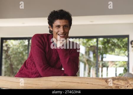 Ritratto di un felice uomo birazziale appoggiato a casa su entresol di legno Foto Stock