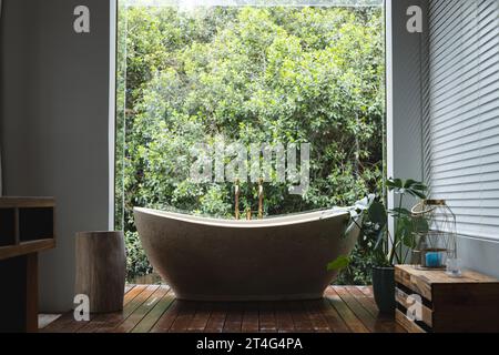 Bagno moderno con enorme finestra con vista sugli alberi nel bagno soleggiato Foto Stock