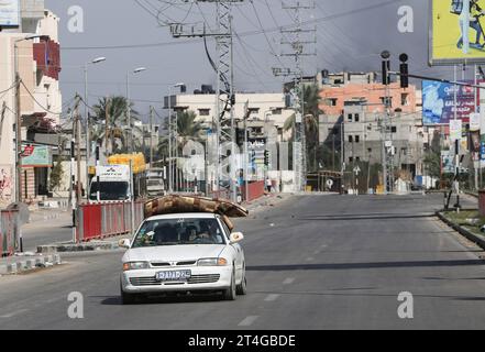 Gaza, Palestina. 30 ottobre 2023. I palestinesi guidano un'auto carica di oggetti personali mentre fumano in sottofondo mentre fuggono dal campo profughi di Nuseirat, nella Striscia di Gaza centrale, in mezzo a continue battaglie tra Israele e il gruppo palestinese Hamas. Migliaia di civili, sia palestinesi che israeliani, sono morti dal 7 ottobre 2023, dopo che i militanti palestinesi di Hamas con base nella Striscia di Gaza sono entrati nel sud di Israele in un attacco senza precedenti che ha innescato una guerra dichiarata da Israele ad Hamas con attentati di rappresaglia a Gaza. Credito: SOPA Images Limited/Alamy Live News Foto Stock