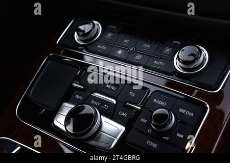 Interni di una moderna auto di lusso. Dettagli del cambio automatico, del sistema di controllo multimediale, del pannello di controllo dell'auto, del pulsante di emergenza rosso della presa d'aria e del cruscotto interno. Auto sportiva Prestige. Messa a fuoco selettiva Foto Stock