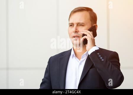 Un uomo d'affari sicuro di sé parla preoccupato al telefono Foto Stock