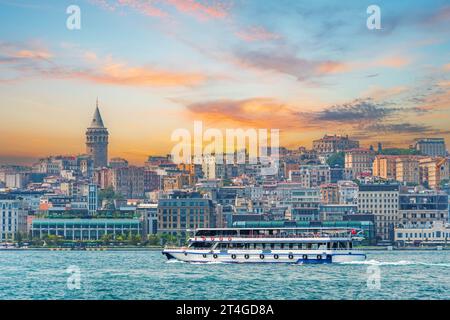 Vista della parte storica centrale di Istanbul con i vecchi edifici e la Torre Galata serale al tramonto, nave e traghetti con persone che galleggiano nel cielo Foto Stock