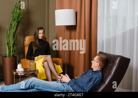 Uomo di mezza età alla nomina di uno psicologo che condivide i suoi problemi Foto Stock