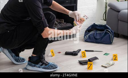 Detective raccolta di prove in una scena di crimine. Specialisti Forensic fare esperienza a casa di una persona morta. Indagine sull'omicidio condotta da un professionista Foto Stock