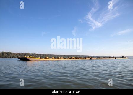 Un rimorchiatore spinge chiatte combinate caricate di sabbia lungo il Danubio Foto Stock