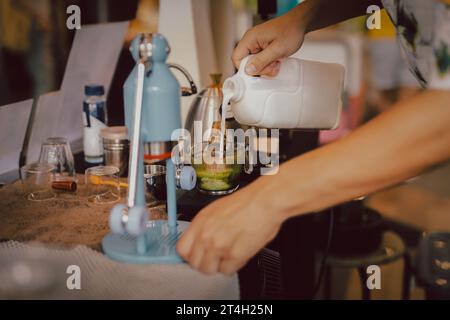 Barista che prepara il latte matcha con il latte versato a mano nella caffetteria. Foto Stock