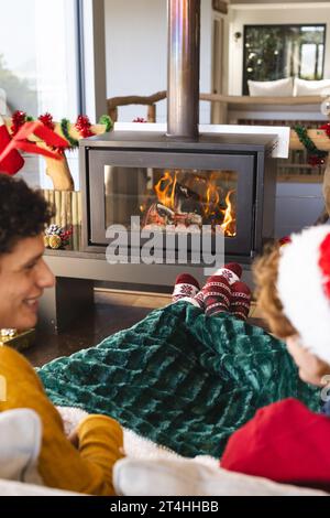 Coppia maschile gay felice e diversificata che parla e indossa abiti di natale a casa Foto Stock