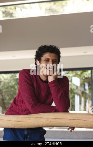 Ritratto di un felice uomo birazziale appoggiato a casa su entresol di legno Foto Stock