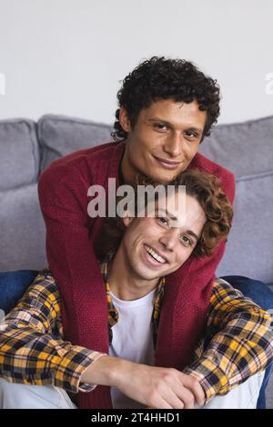 Ritratto di una coppia di maschi gay felice e diversificata che si abbraccia a casa Foto Stock