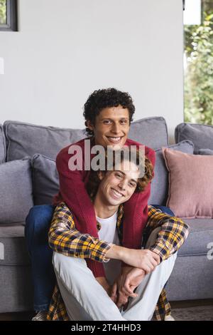 Ritratto di una coppia di maschi gay felice e diversificata che si abbraccia a casa Foto Stock