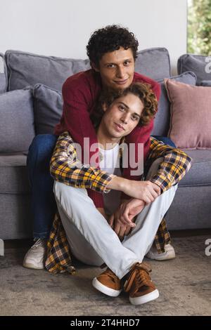 Ritratto di una coppia di maschi gay felice e diversificata che si abbraccia a casa Foto Stock