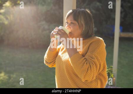 Donna birazziale anziana felice che beve tè in giardino Foto Stock