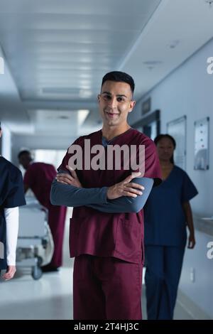 Ritratto di felice medico maschio birazziale che indossa scrub in ospedale Foto Stock